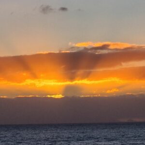 Sun rays setting through stormy clouds over the sea in Kapiti