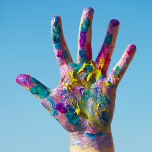 Hand covered in paint splotches reaching out in the blue sky How the Feng Shui Elements Affect Your Body - Equate Feng Shui